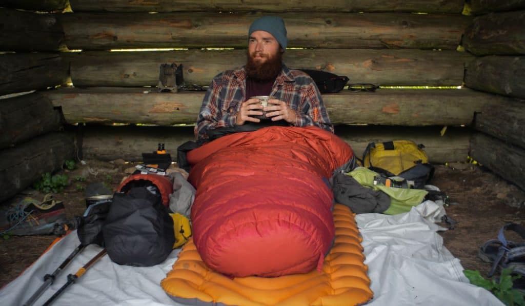 male hiker laying on the ground in his sleeping bag

