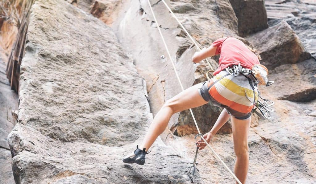 Athletic strong man climbing a rock wall