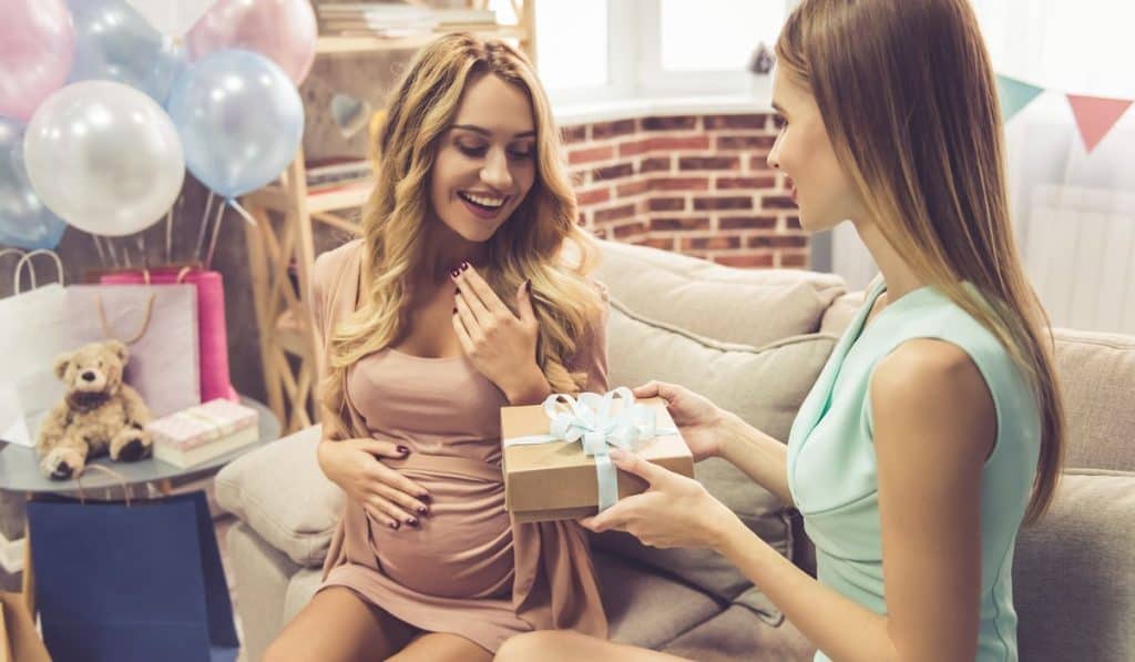 lady giving a gift to her pregnant friend at her baby shower