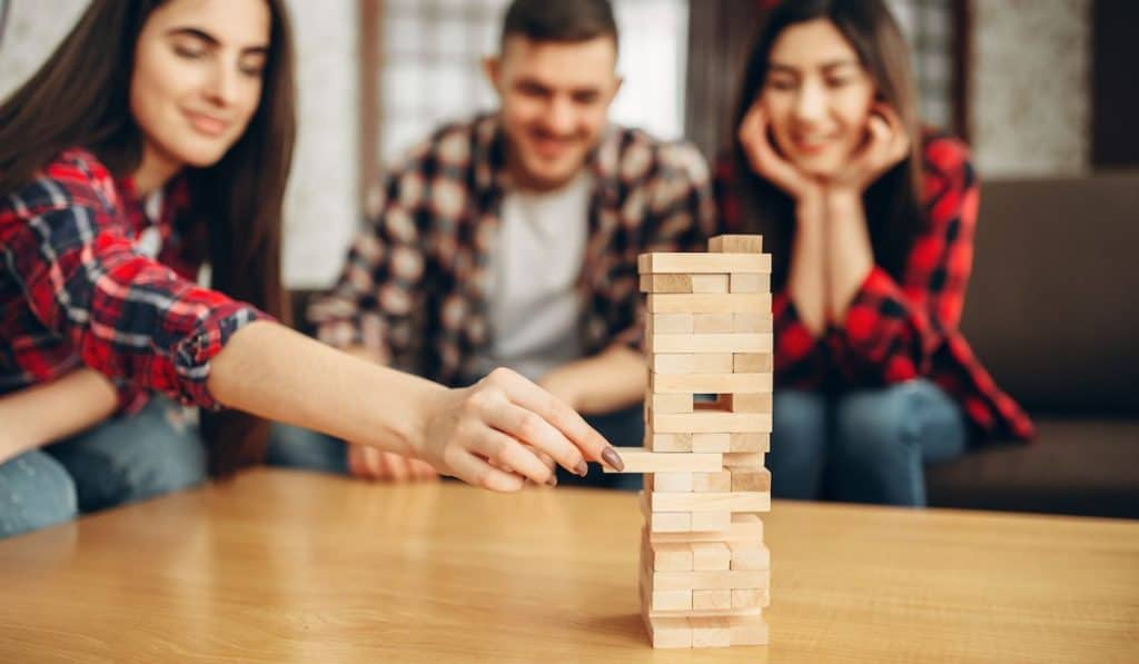 Smiling friends plays jenga table game at home