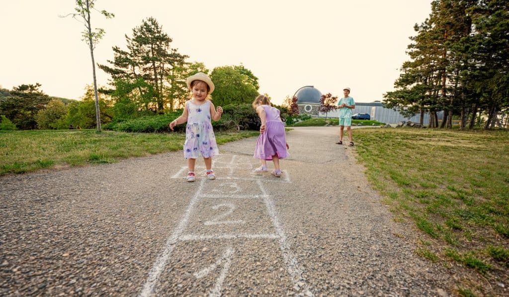 Two sisters playing hopscotch in park