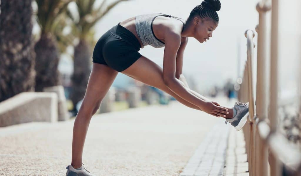 Woman stretching legs preparing for running in the park