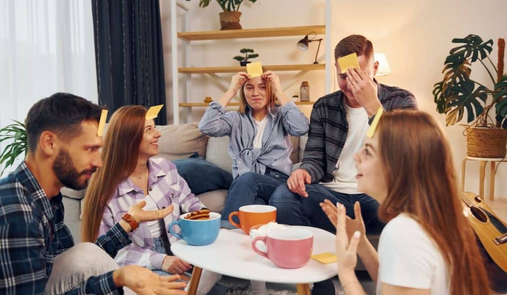 Yellow stickers on forehead. Group of friends have party indoors together
