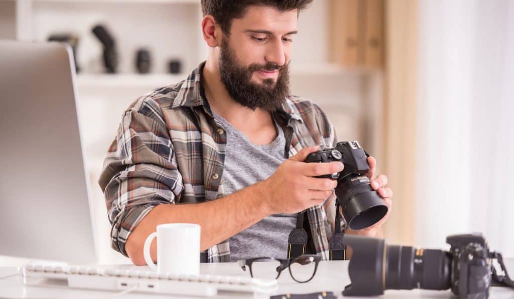 male photographer looking at the shots from his dslr camera