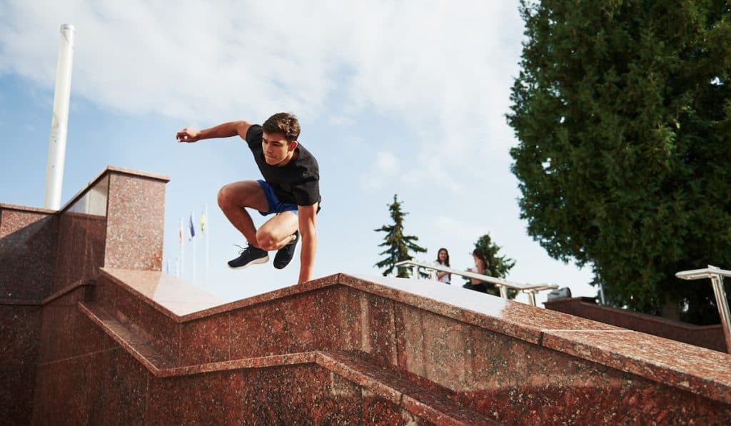 Young sports man doing parkour in the city at sunny daytime