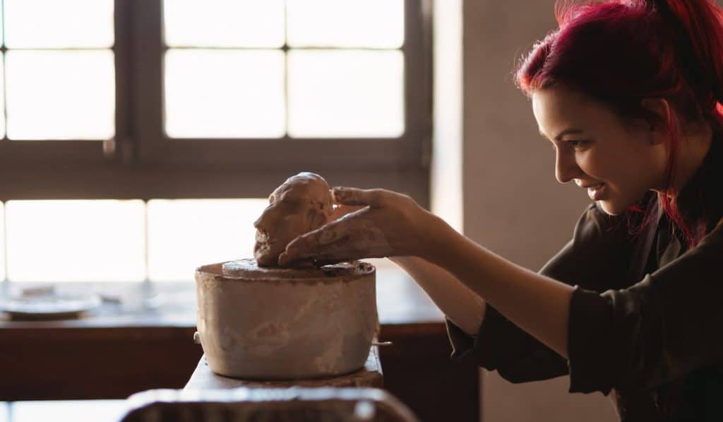 Young woman sculptor artist creating a bust sculpture with clay in an art studio