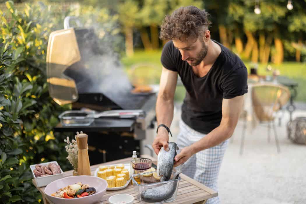 a man cooking fish and vegetables in the yard
