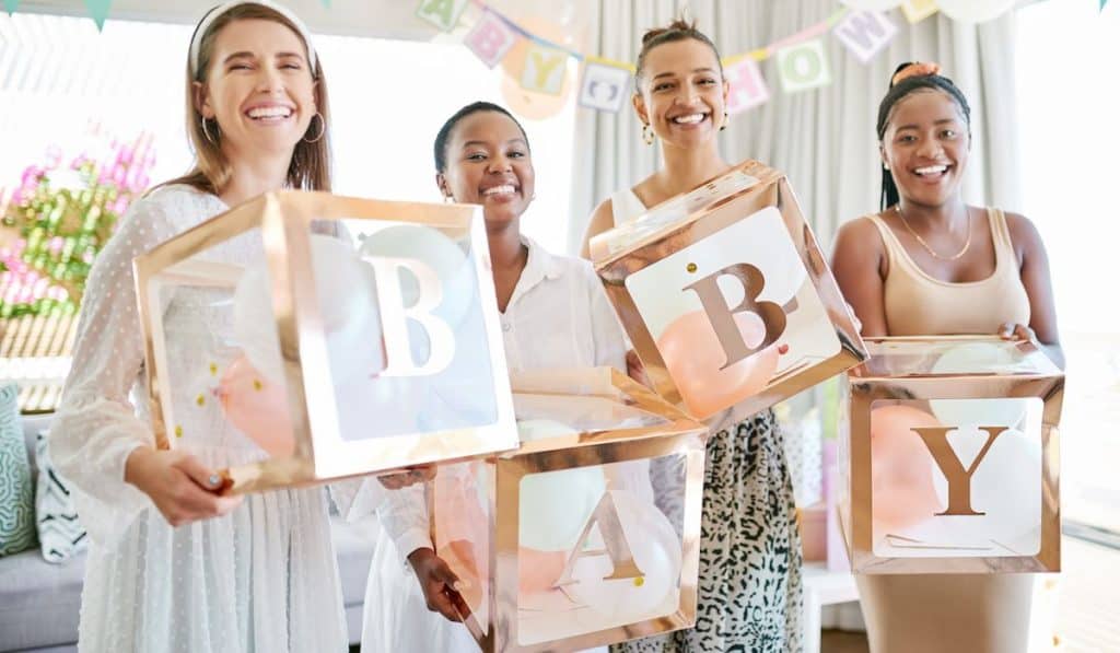 friends at a baby shower holding cute cubes with B A B Y letters on it