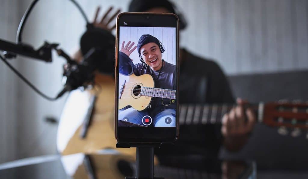 influencer playing guitar recording himself for his YouTube channel