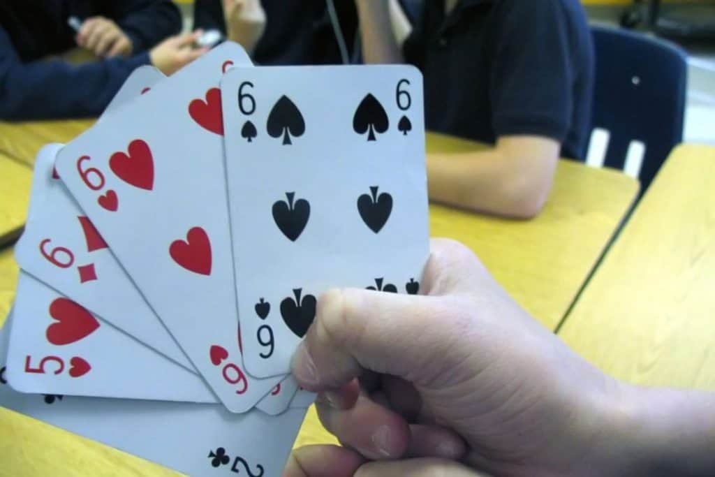 kid holding three six cards and one five card