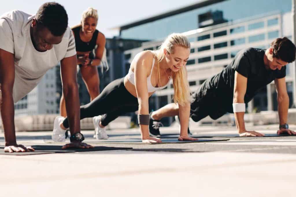 men and women doing push ups outdoors