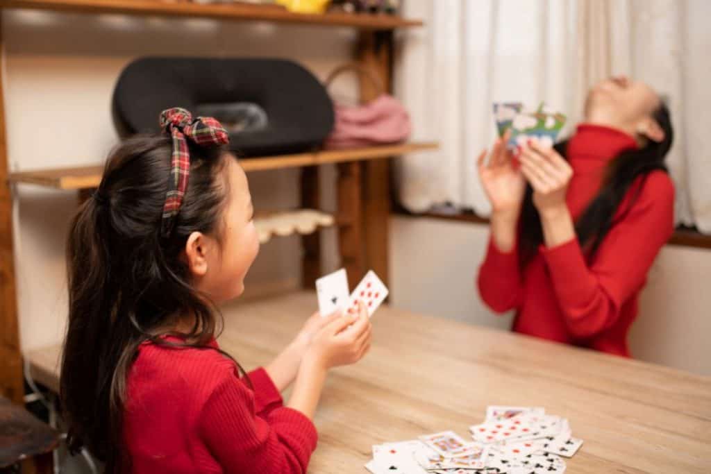 mother and daughter playing cards on the dining table