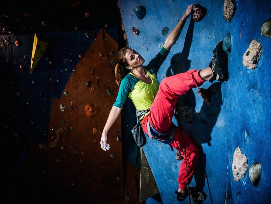 strong young woman doing indoor rock climbing