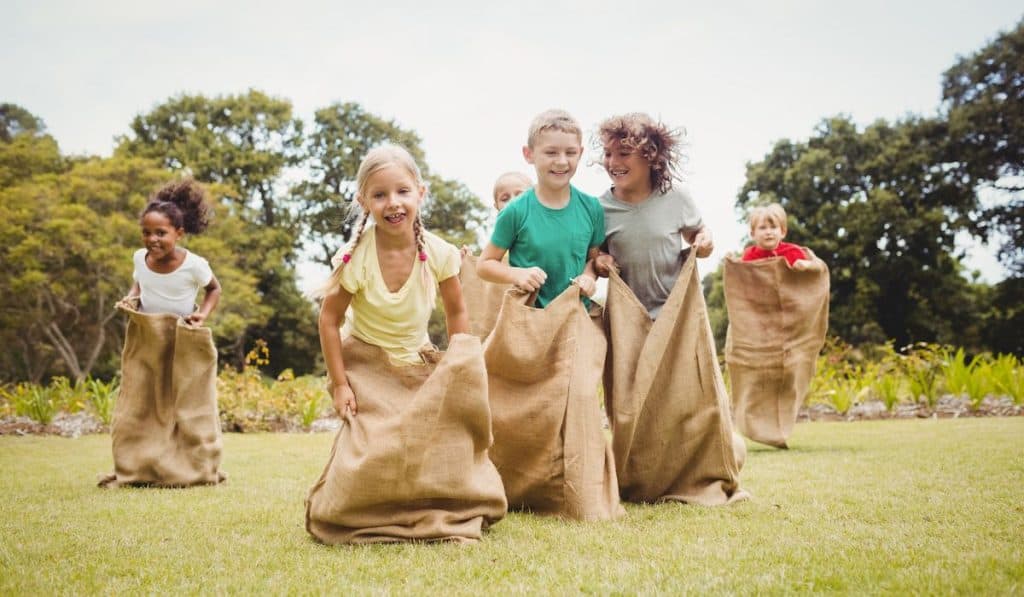 Children having a sack race in park on a sunny day

