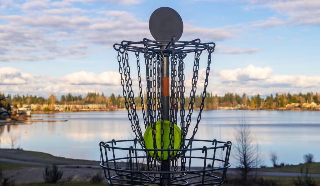 Disc gold basket on a lake front park under blue sky