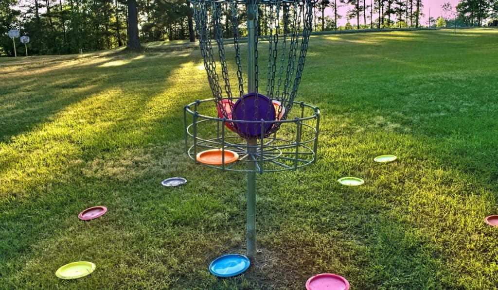 Disc gold basket with colorful discs inside and outside in the park