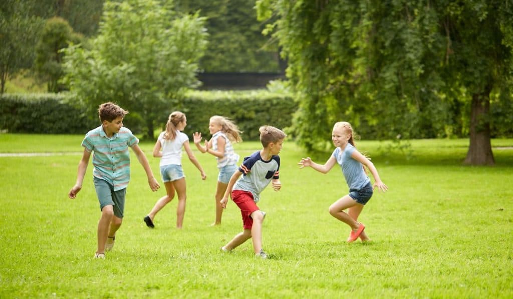 Group of kids playing tag games in summer park