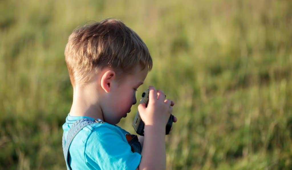Little boy trying to make photos with camera outdoor

