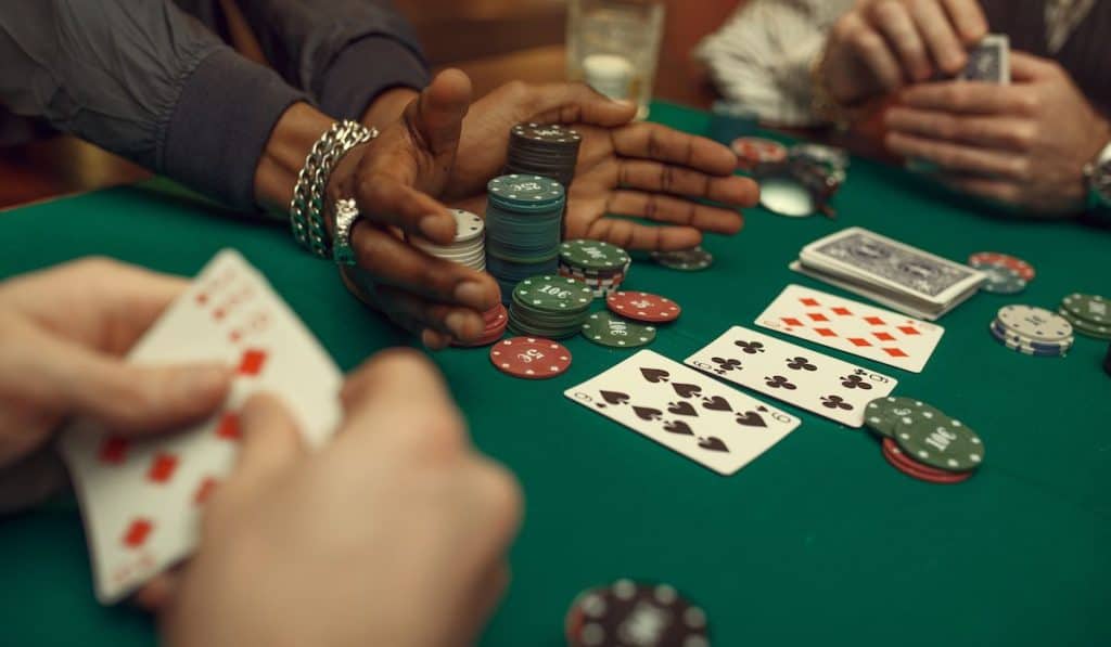 Poker players hands, gaming table on background
