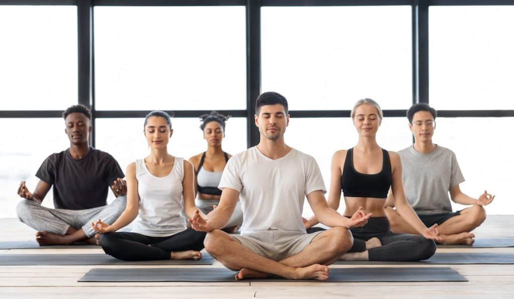 young multiethnic men and woman meditating together in lotus position