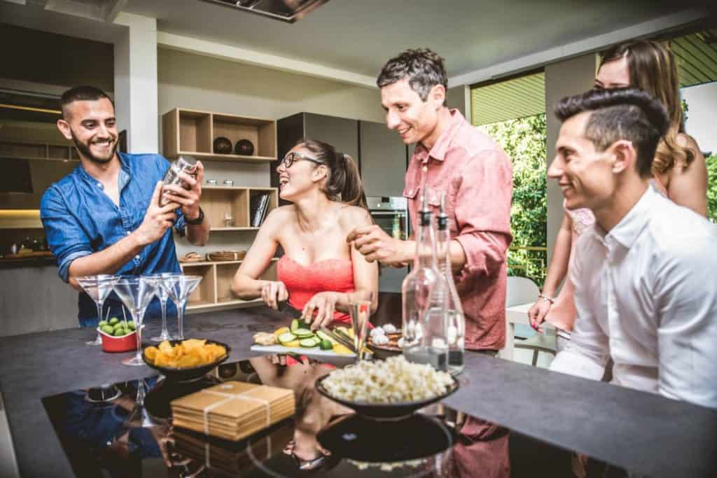 a group of friends having fun doing a cocktail missing challenge in the kitchen area