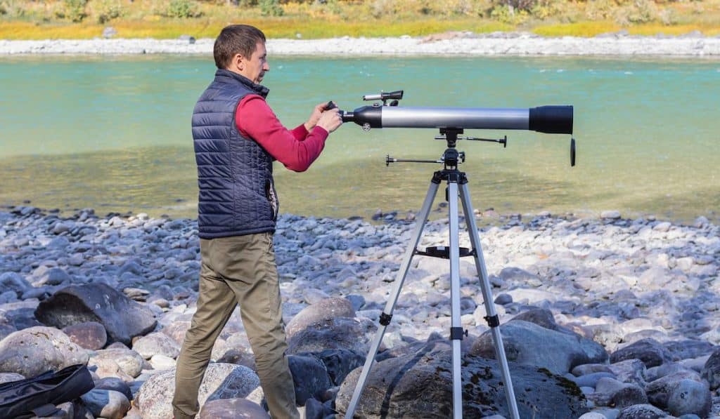 astronomer adjusts optical magnifier for viewing at sky with telescope