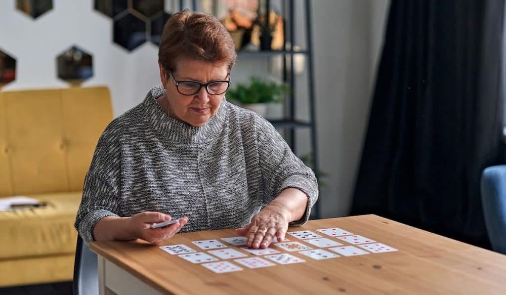senior woman playing solitaire at home