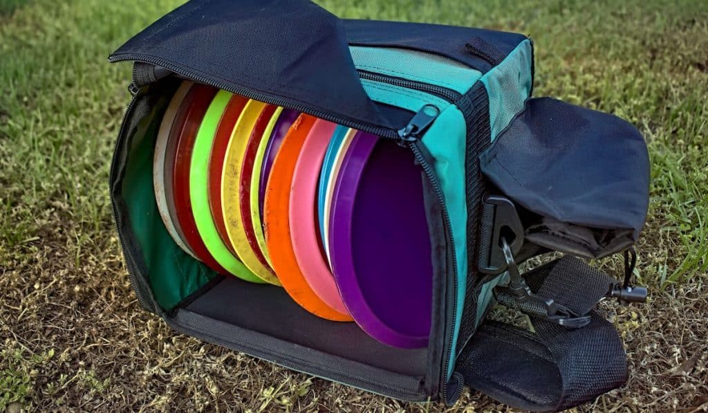 Bag of disc golf discs laying on grass