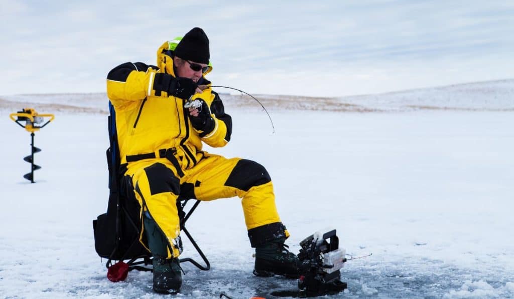 Ice fisherman with a fish on his line.
