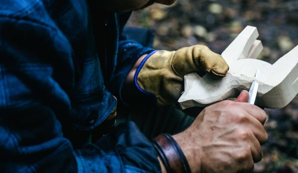 Man Holding Whittling Knife Carving Wooden Horse
