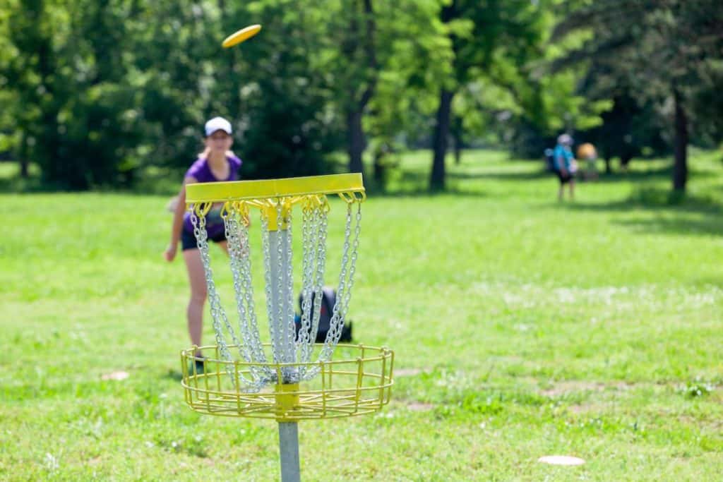 Young woman playing flying disc sport game in the park
