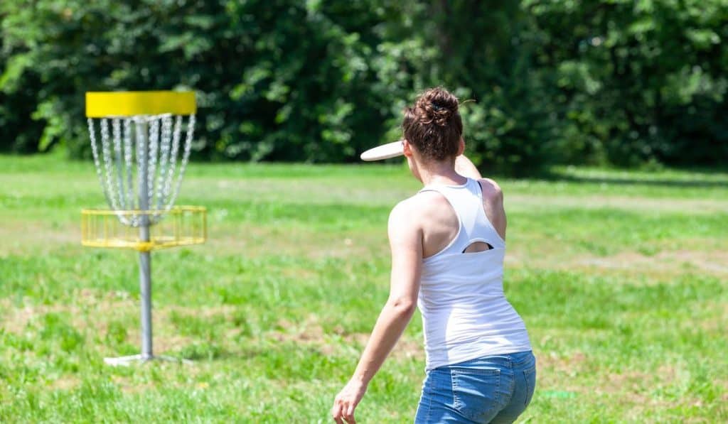 Young woman playing flying disc sport game in the park
