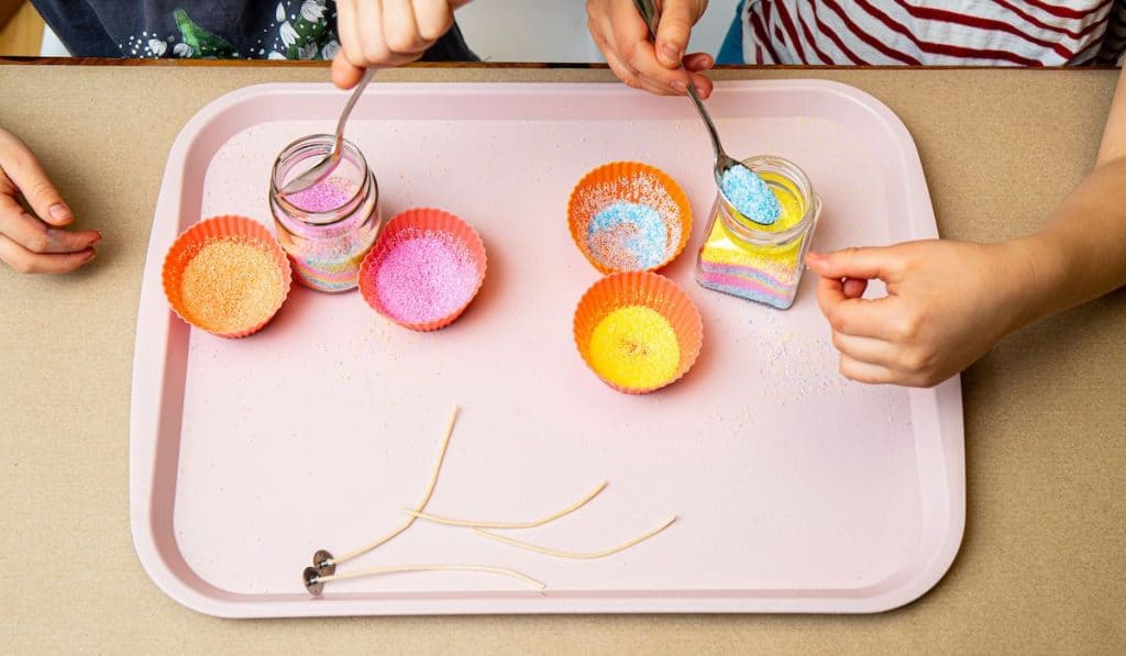 Young children making fun colorful layered granulated wax candles at home