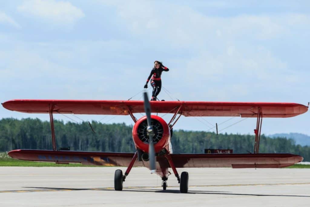 a woman standing on the wings of an airplane about to take off