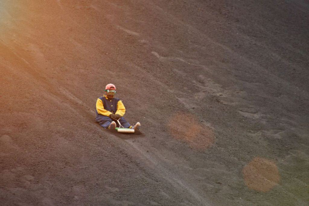 A man in protective gears enjoying volcano boarding