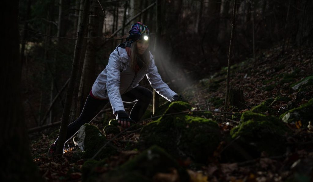 Beauty tourist woman with headlight in the forest
