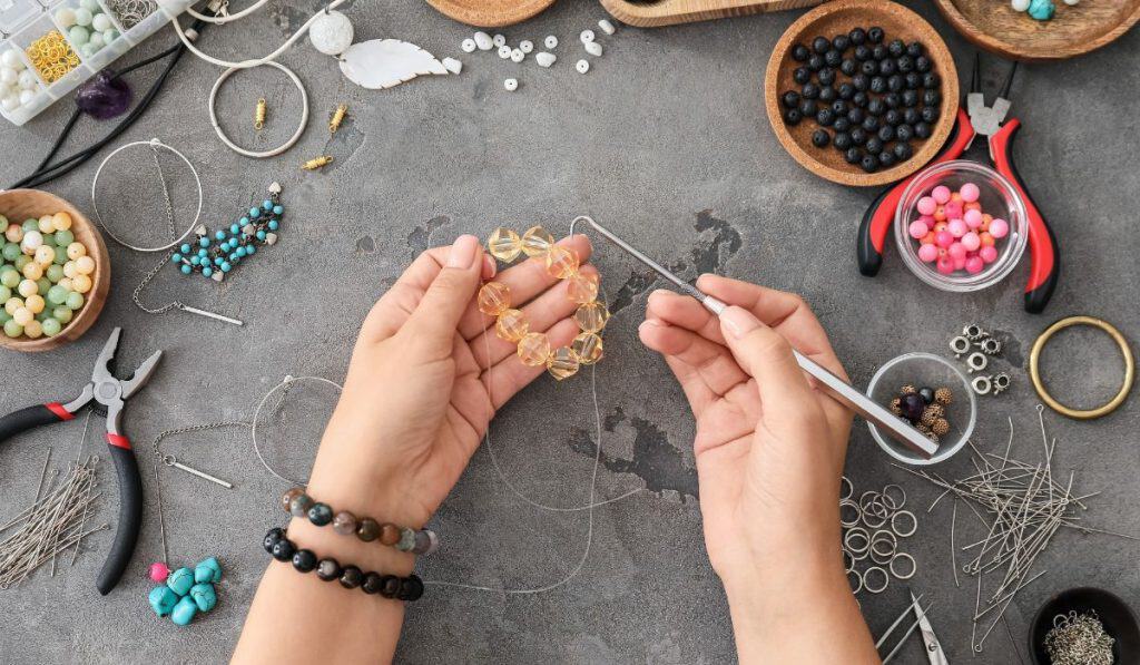Female designer making jewelry, top view
