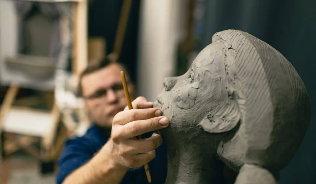 Man sculptor creates sculpt bust clay human