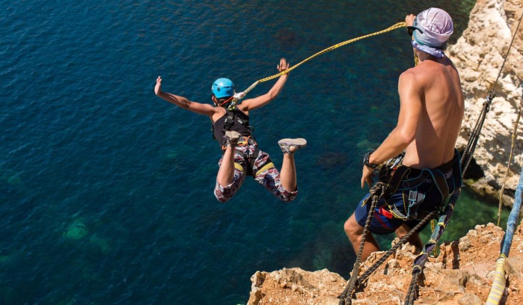 Rope jumping off a cliff with a rope in the water