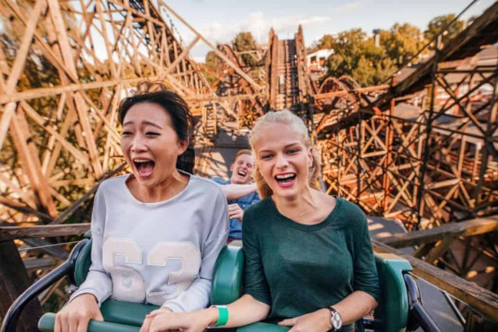 friends riding a roller coaster in a theme park 