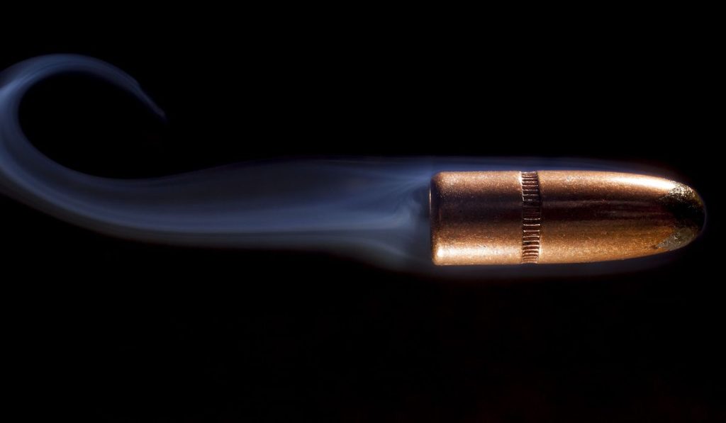 Copper plated bullet with smoke behind that is going fast
