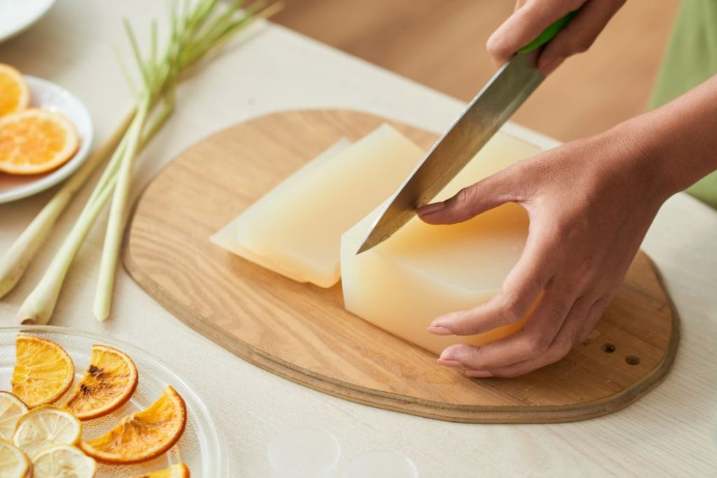 a woman cutting a home made soap into equal cuts using a knife