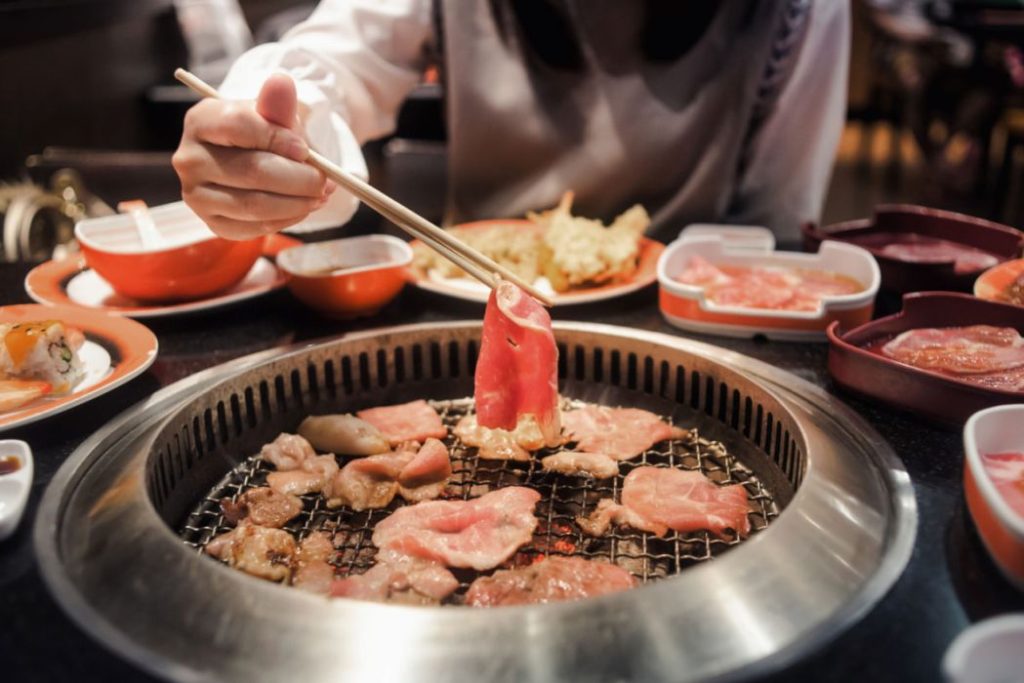 a woman eating grilled pork in a restaurant 