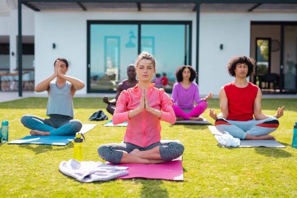 Diverse friends practicing yoga and meditating in garden
