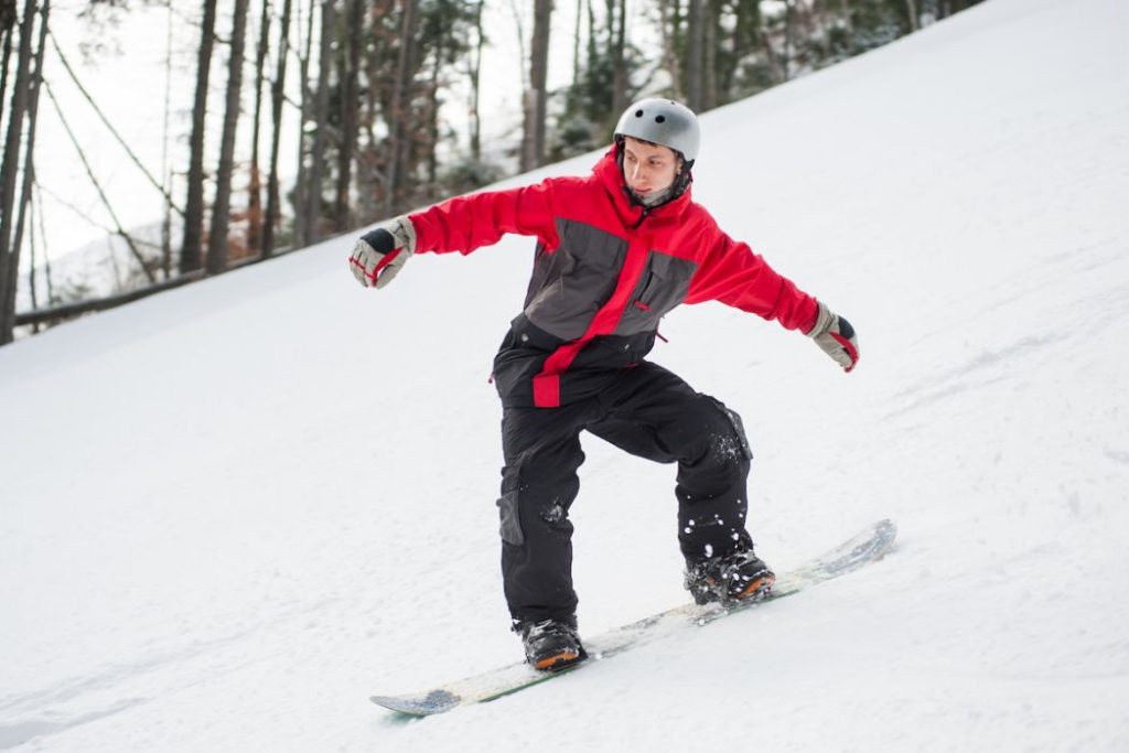 Male snowboarder riding down from the mountain in winter day
