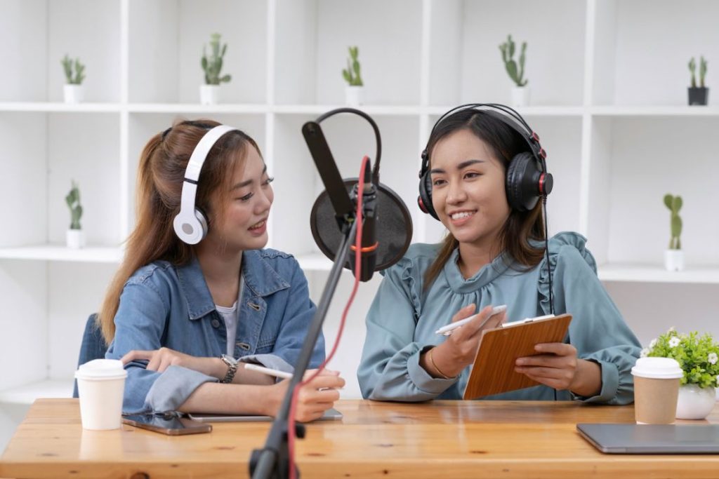 Young women recording podcast in broadcasting at studio together