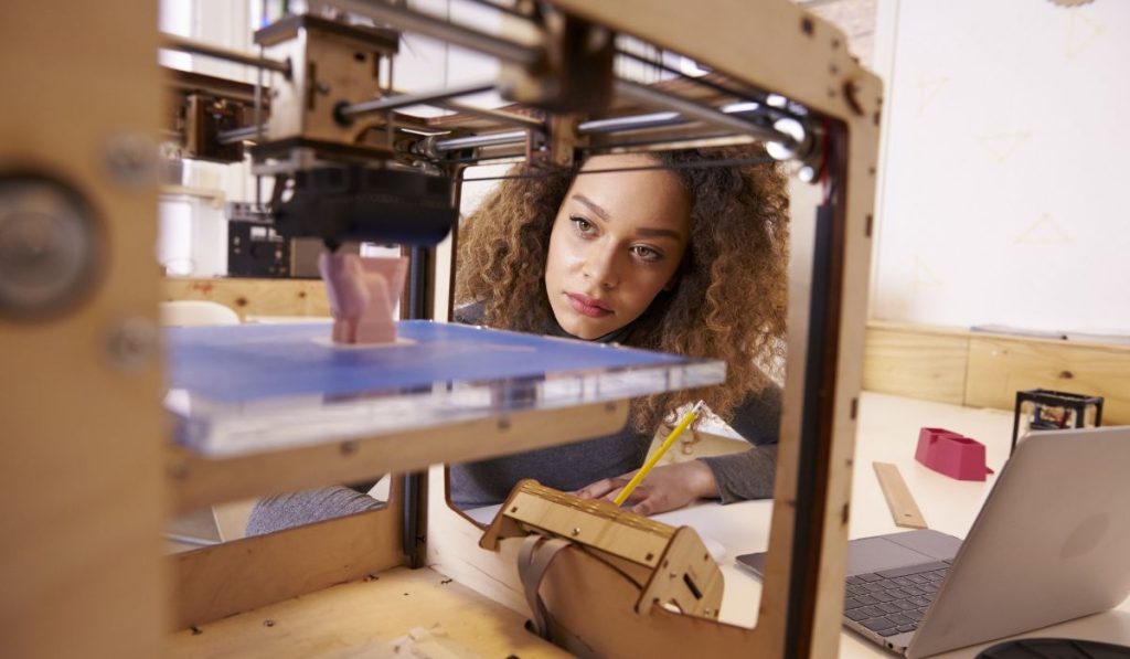 Female Designer Working With 3D Printer In Design Studio
