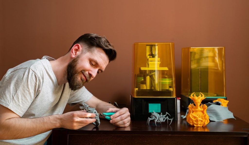 Man cutting rests of 3d printer figurine with cutters
