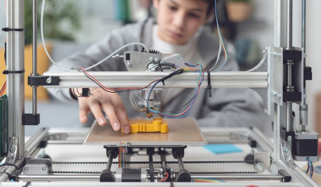 boy printing a prototype using a 3D printer
